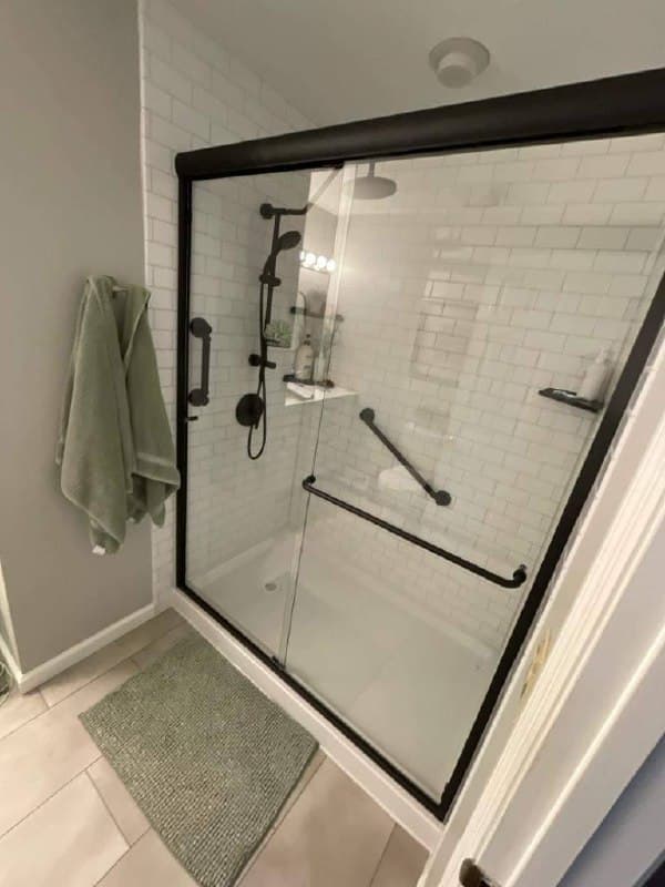 Completed shower transformation with matte black trim and sliding glass door