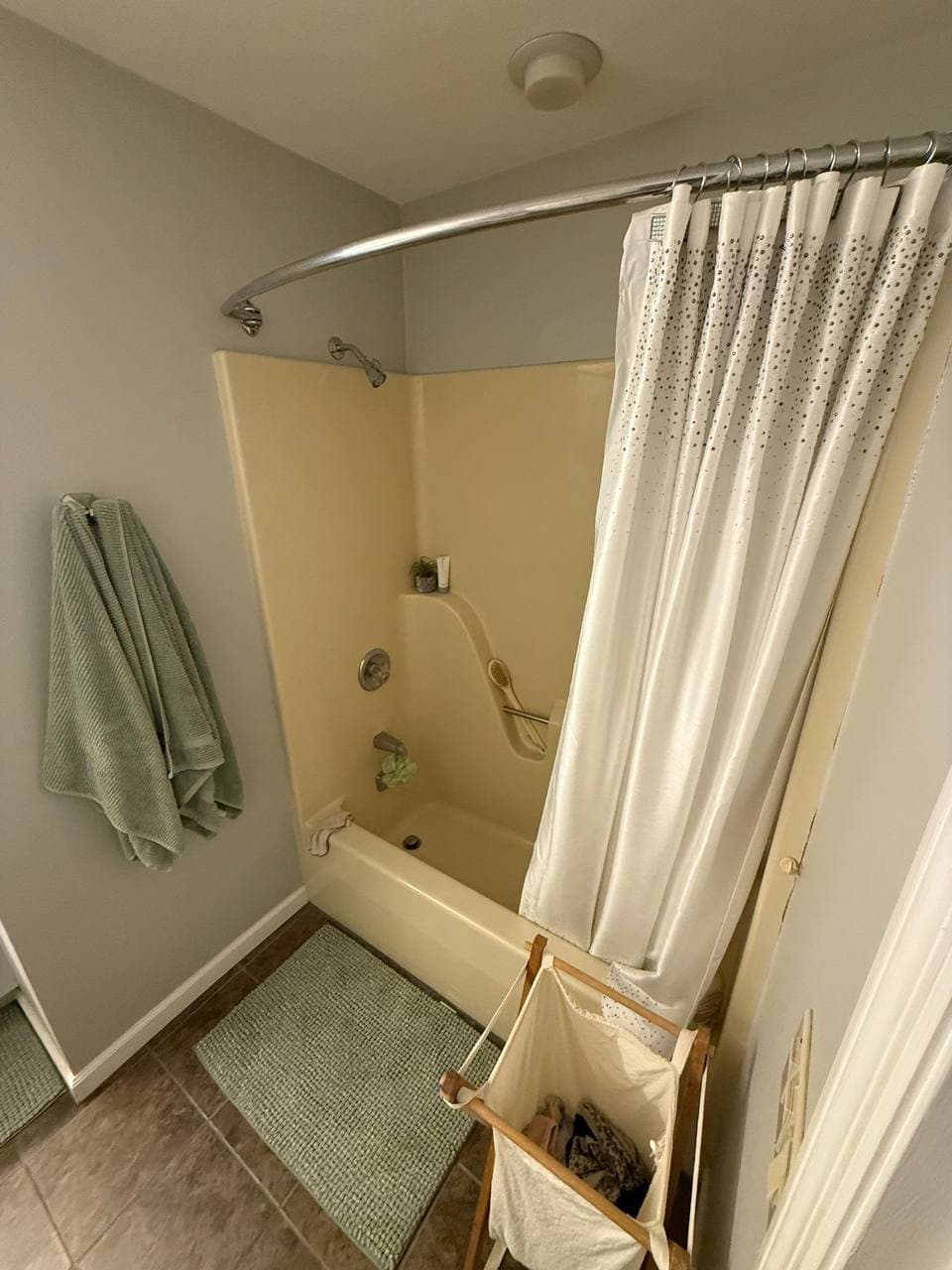 Outdated bathroom before renovation — old yellow tub with shower curtain